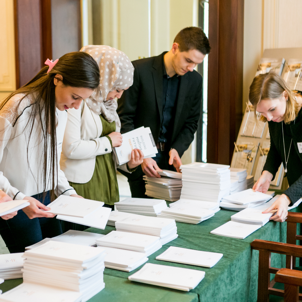 L’équipe de Poseco en pleine séance de travail au Parlement belge, réunie autour d’une table de réunion, échangeant sur des documents et des dossiers.